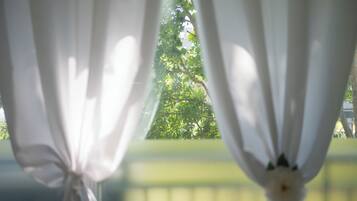 Vista a través de cortinas blancas traslúcidas sobre un fondo verde borroso.