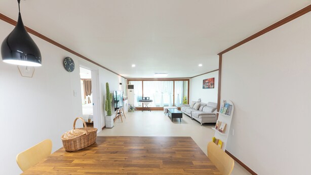 A spacious living area with a wooden dining table, two chairs, a sofa, and a coffee table. - TOV STAY (Pyeongtaek)