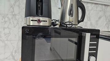 A microwave oven with a digital display, a toaster, and a kettle on top.