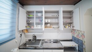 A kitchen with white cabinets, a stainless steel sink, and a tiled backsplash. - TOV STAY (Pyeongtaek)