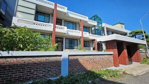 A multi-story building with a brick facade, large windows, and a balcony with decorative railings. - TOV STAY (Pyeongtaek)