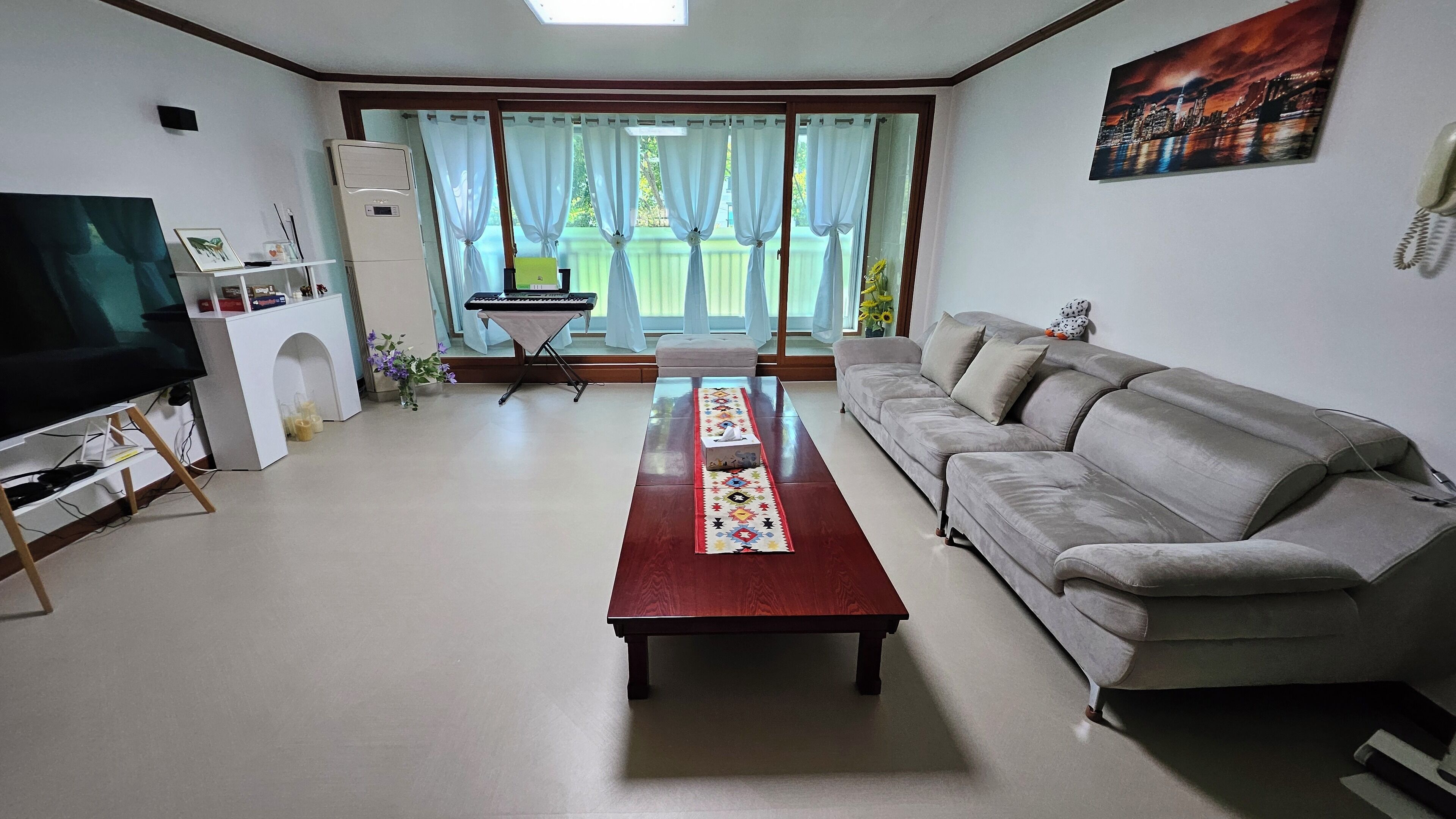 Una sala de estar con sofá, televisión, mesa de centro y ventana con cortinas.