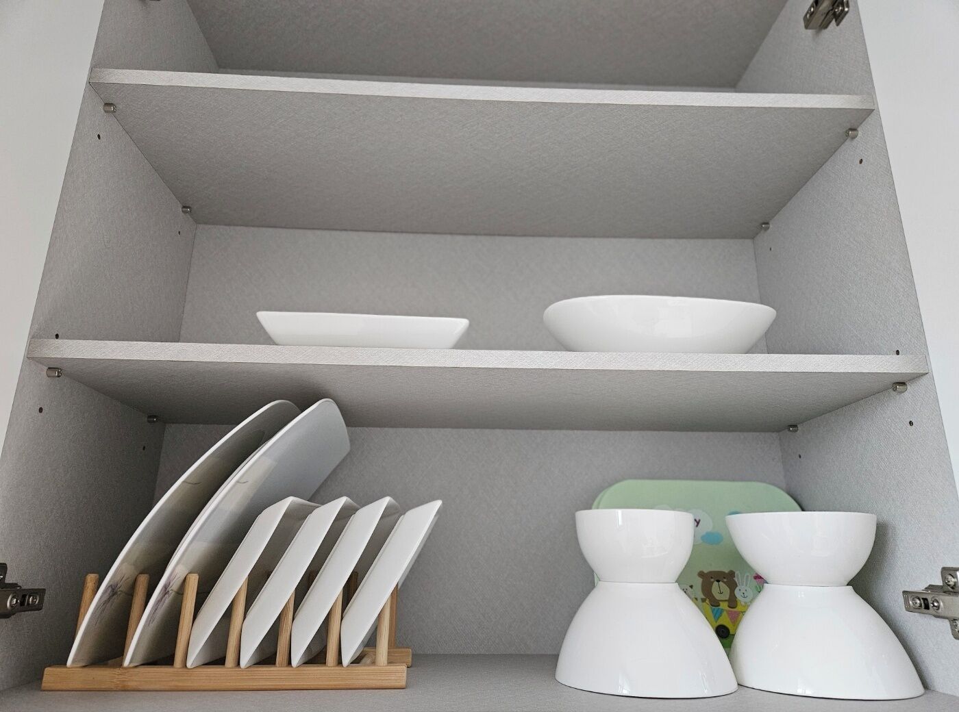 Una cocina con armarios blancos y un portalápices de madera.