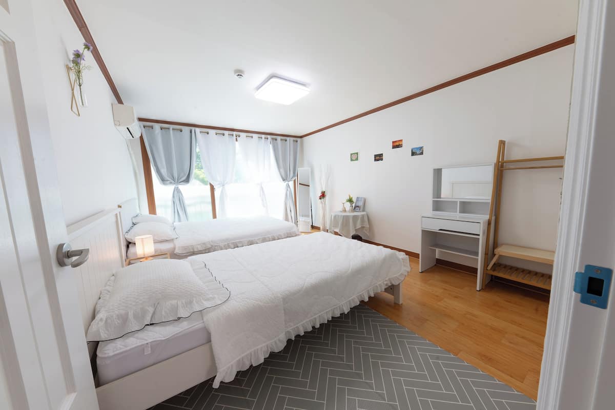 Un dormitorio con dos camas, un escritorio y una silla.