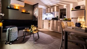 A modern kitchen with a central island, a dining area with a table and chairs, and a living area with a sofa and a small table. - 26m² Mobile Home for 6 with Jacuzzi and Terrace (Agde)