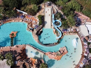 An aerial view of a resort with multiple swimming pools, a water slide, and lounge areas. - 26m² Mobile Home for 6 with Jacuzzi and Terrace (Agde)