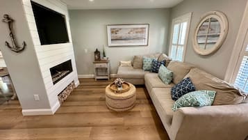 A living room with a fireplace, a sofa, a coffee table, and a painting on the wall.