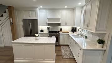 A modern kitchen with white cabinetry, stainless steel appliances, and a marble countertop.