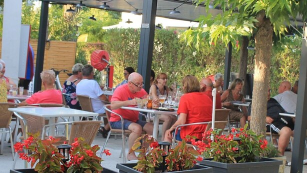 An outdoor patio area with tables and chairs, surrounded by potted plants and trees. - 31m² Mobile Home with Terrace - 3 Bedrooms, Sleeps 6 (La Grande-Motte)
