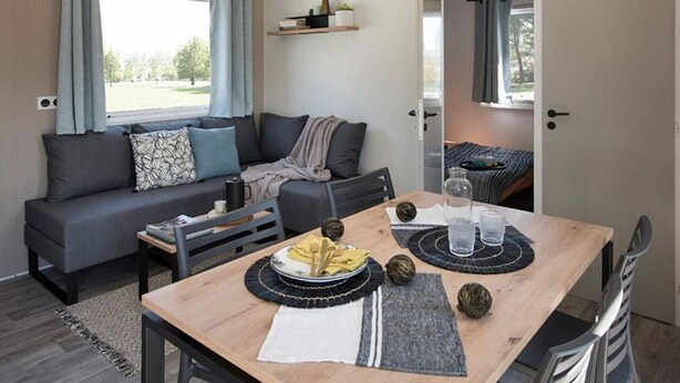 Um espaço de estar moderno e compacto, com sofá, mesa de jantar e pequena cozinha.
