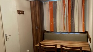 Un coin repas avec une table et des chaises en bois, un banc et une fenêtre agrémentée de rideaux à rayures.