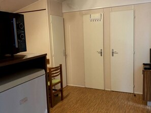Ein kleines Zimmer, ausgestattet mit einer Küchenzeile, einem Holzstuhl und einem zweitürigen Kleiderschrank.