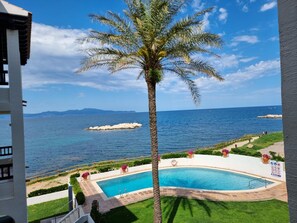 A pool with a view of the sea, a palm tree, and a sign with symbols. - Modern apartment with terrace and pool 50m from the beach (L'Escala)
