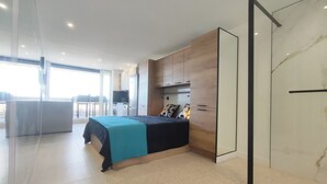Ein modernes Schlafzimmer mit einem Bett, einer kleinen Küchenzeile und einer Glastrennwand.