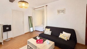 A modern living room with a black sofa, a wooden coffee table, a hanging light fixture, and a framed picture on the wall. - Studio 1 Room Center Ajaccio - Air Conditioning, Sleeps 4 (Ajaccio)