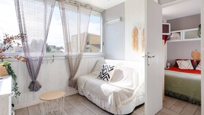 Um quarto acolhedor com uma cama, uma mesa pequena e uma janela com cortinas leves.