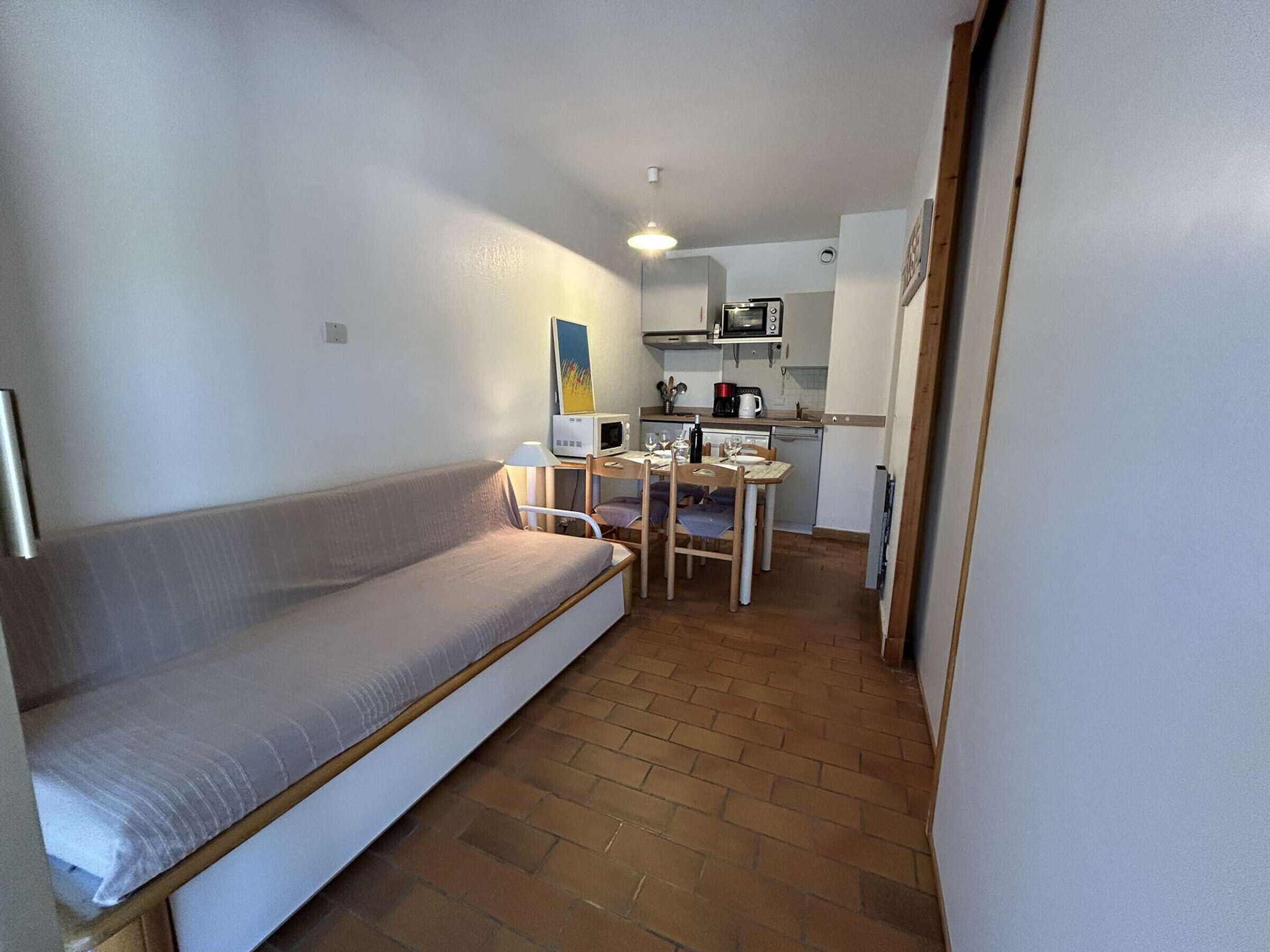 A compact living space with a sofa, a dining table, and a kitchenette.