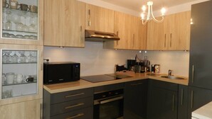 Eine moderne Küche mit Holzschränken, einer schwarzen Mikrowelle, einem Einbauofen und einem Spülbecken.