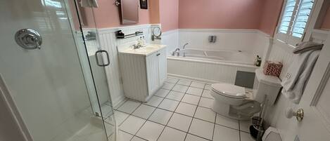 A bathroom with a glass shower enclosure, a white sink, a bathtub, and a toilet.