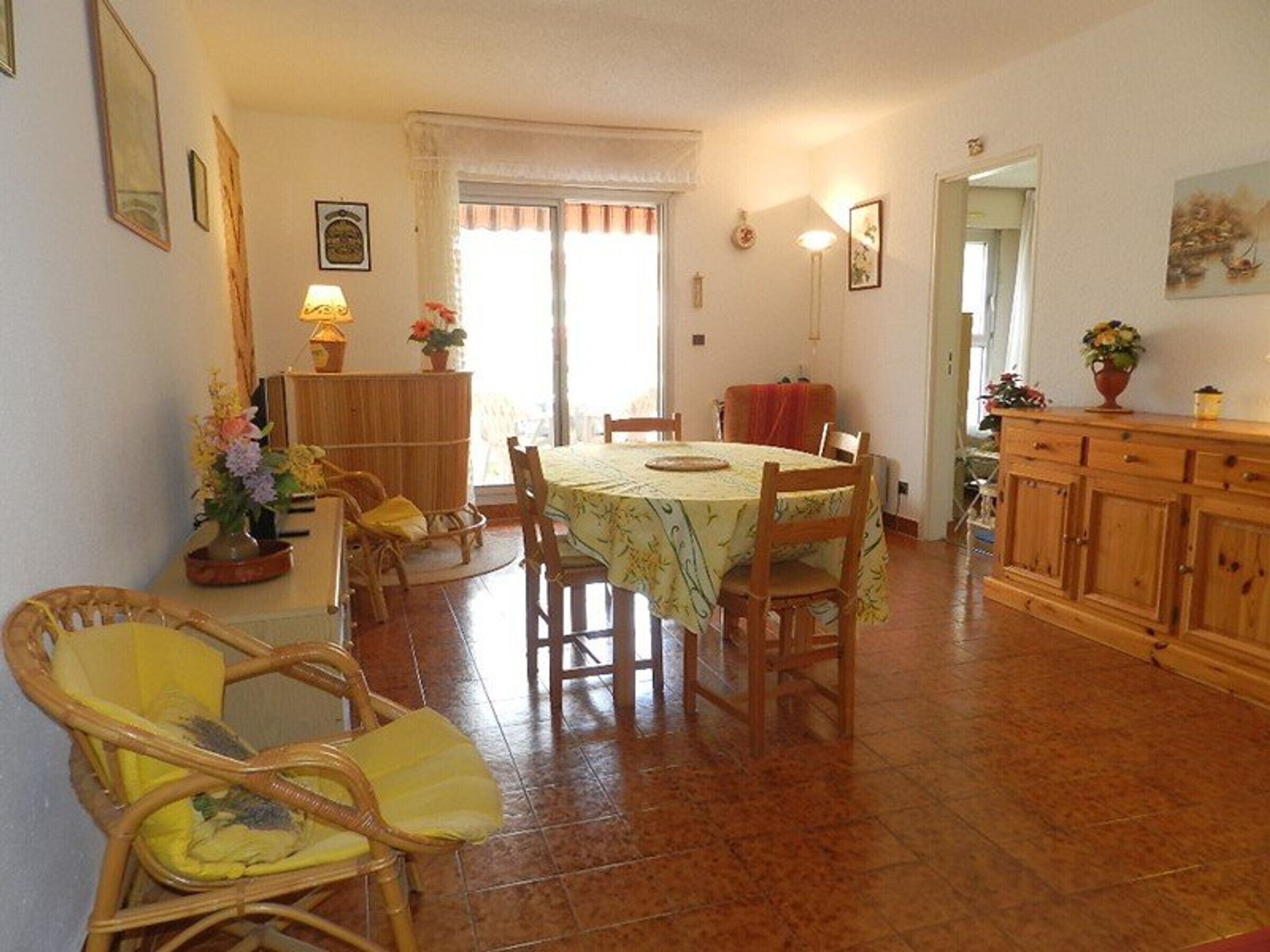 A dining area with a round table, chairs, a buffet counter, and a kitchen area.