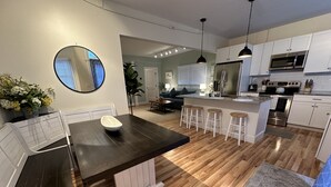 A modern kitchen with a dark countertop, white cabinets, and a central island with stools. - 86 Dr Marcus House - Popular Broadway Area 6 Bedroom Home (Newport)