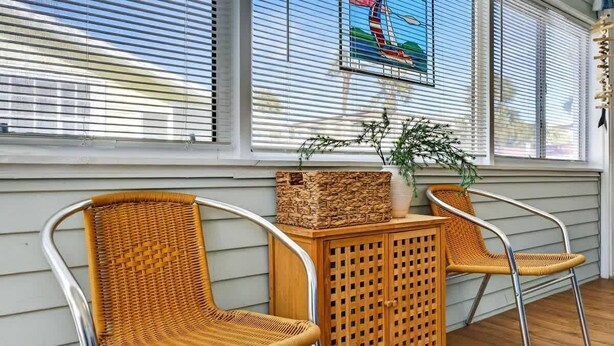 A porch with two wicker chairs, a wooden table, and a wicker basket. - Sunny Isles Beach Cottage, Indian Shores! (Indian Shores)