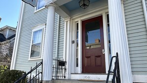 A two-story house with a front porch, a red door, and a sign indicating 'Spring Street'. - Exposed Brick Suite 1 Bed/ 1 Bath/ Pullout Sofa 1 Bedroom Apts (Newport)