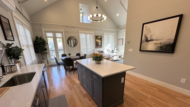 A spacious kitchen with a central island, wooden flooring, and a dining area with a round table and chairs. - Brand New Construction! 2bed/1bath W/private Deck - Unit 2 2 Bedroom Apts (Newport)