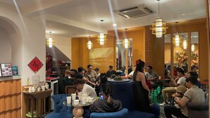Un restaurante con mesas redondas, sillas azules y lámparas colgantes.