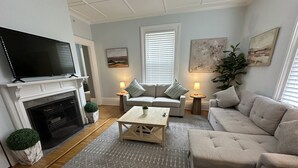 A living room with a fireplace, a television, a sofa, a coffee table, and a rug. - Spacious Suite 1 Bed/ 1 Bath/ Pullouts Sofas - Unit 5 1 Bedroom Apts (Newport)