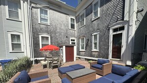 A patio area with wicker furniture and a red umbrella. - Spacious Suite 1 Bed/ 1 Bath/ Pullouts Sofas - Unit 5 1 Bedroom Apts (Newport)