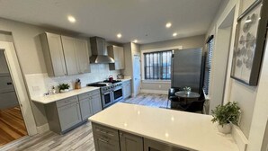 Eine moderne Küche mit grauen Schränken, einer weißen Arbeitsplatte und einem eingebauten Backofen.