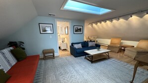 A living room with a blue sofa, a red couch, a coffee table, and a patterned rug. - Unique 2 Bed 1 Bath Apartment Off Broadway #3 2 Bedroom Apts (Newport)