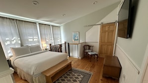 A bedroom with a bed, wooden floor, patterned rug, and a TV mounted on the wall. - Large & Unique Two Bedroom Apartment Downtown #17 2 Apts (Newport)
