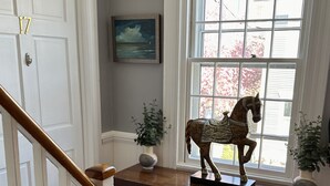 A staircase with a wooden handrail, a wooden table with a horse sculpture, two potted plants, and a painting on the wall. - Large & Unique Two Bedroom Apartment Downtown #17 2 Apts (Newport)