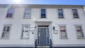 A two-story building with a gray door and a small porch with steps. - Large & Unique Two Bedroom Apartment Downtown #17 2 Apts (Newport)