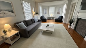 Een moderne woonkamer met een grijze bank, een witte salontafel en een open haard.