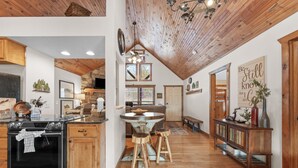 A spacious kitchen with wooden cabinets, a large stove, and a dining area with stools. - Sbl51 The Hunt Cabin At Stonebridge 2 Bedroom Cabin (Branson West)