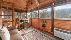 A cozy cabin interior with wooden walls, a dining area, a large window with a view of trees, and mounted animal heads on the ceiling. - Sbl51 The Hunt Cabin At Stonebridge 2 Bedroom Cabin (Branson West)