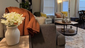 A living room with a sofa, a coffee table, a lamp, and a vase of flowers. - Pet-Friendly 3BR Fire Pit & Games Near Sea World (San Antonio)