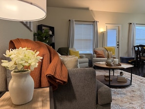 A living room with a sofa, a coffee table, a lamp, and a vase of flowers. - Pet-Friendly 3BR Fire Pit & Games Near Sea World (San Antonio)