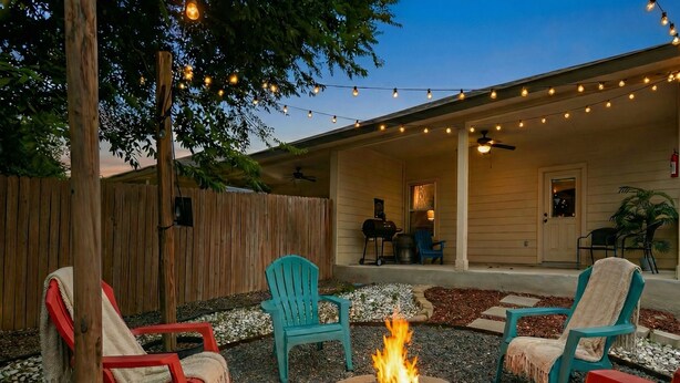 A patio with outdoor seating, a fire pit, and string lights. - Pet-Friendly 3BR Fire Pit & Games Near Sea World (San Antonio)