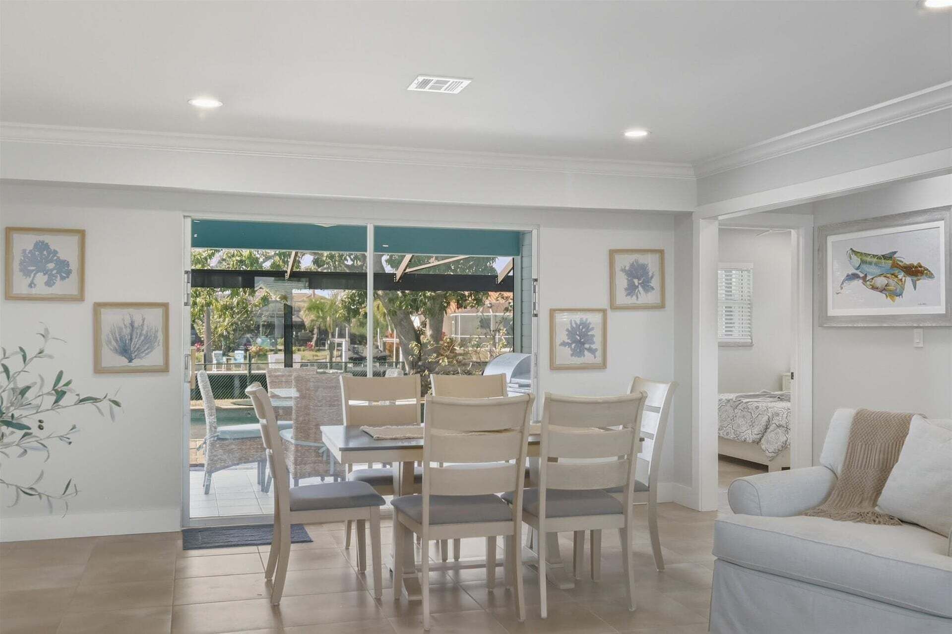 A spacious living area with a dining set, a sofa, and a view of the outdoors.