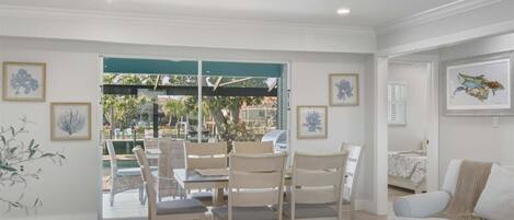 A spacious living area with a dining set, a sofa, and a view of the outdoors.