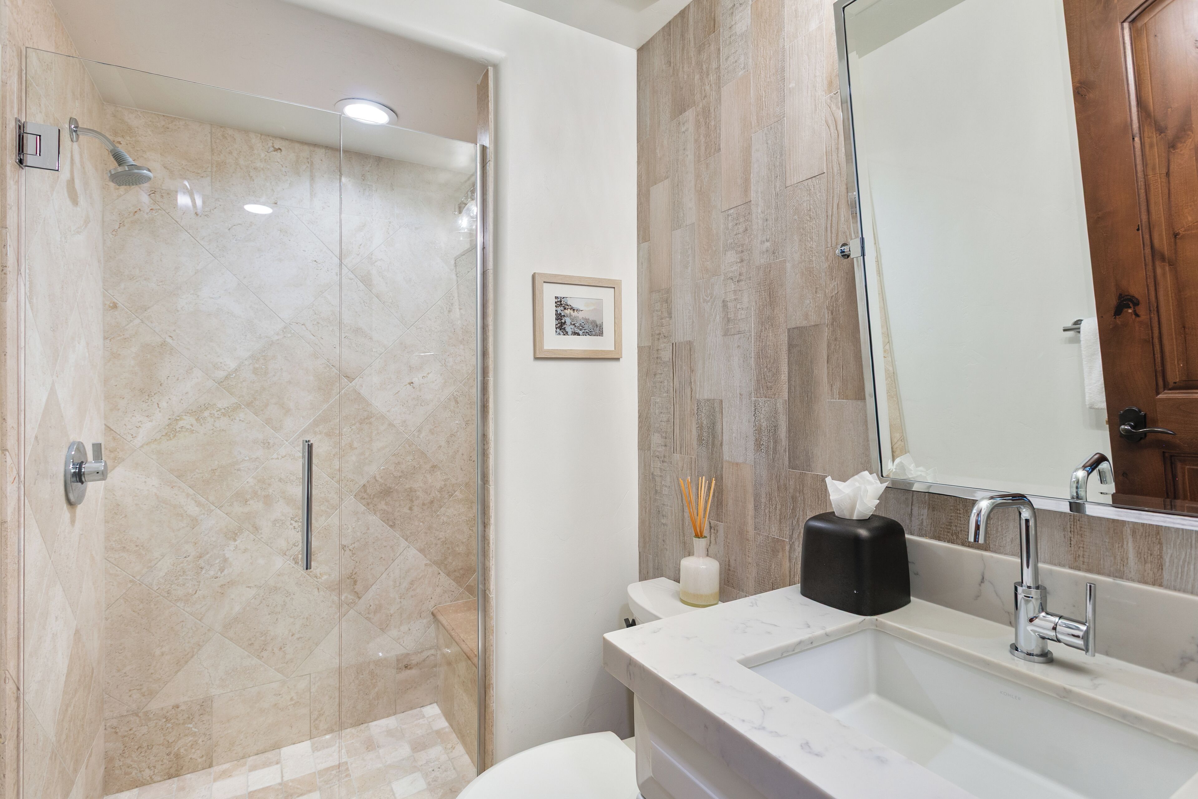 Une salle de bain moderne avec une douche à parois de verre, un lavabo en marbre et un meuble en bois.