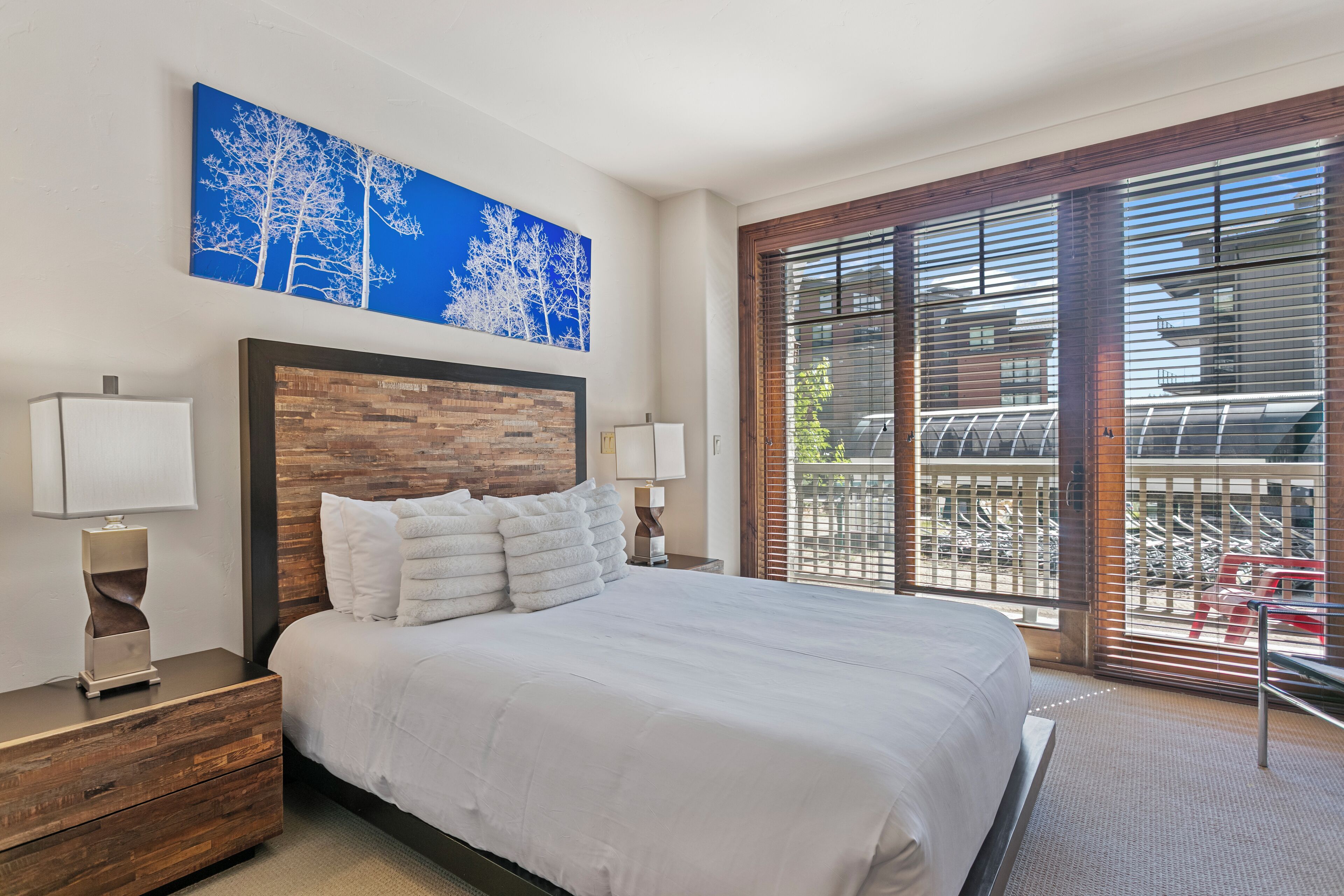 Un dormitorio con una cama grande, cabecera de madera y vistas a un balcón con una silla roja.
