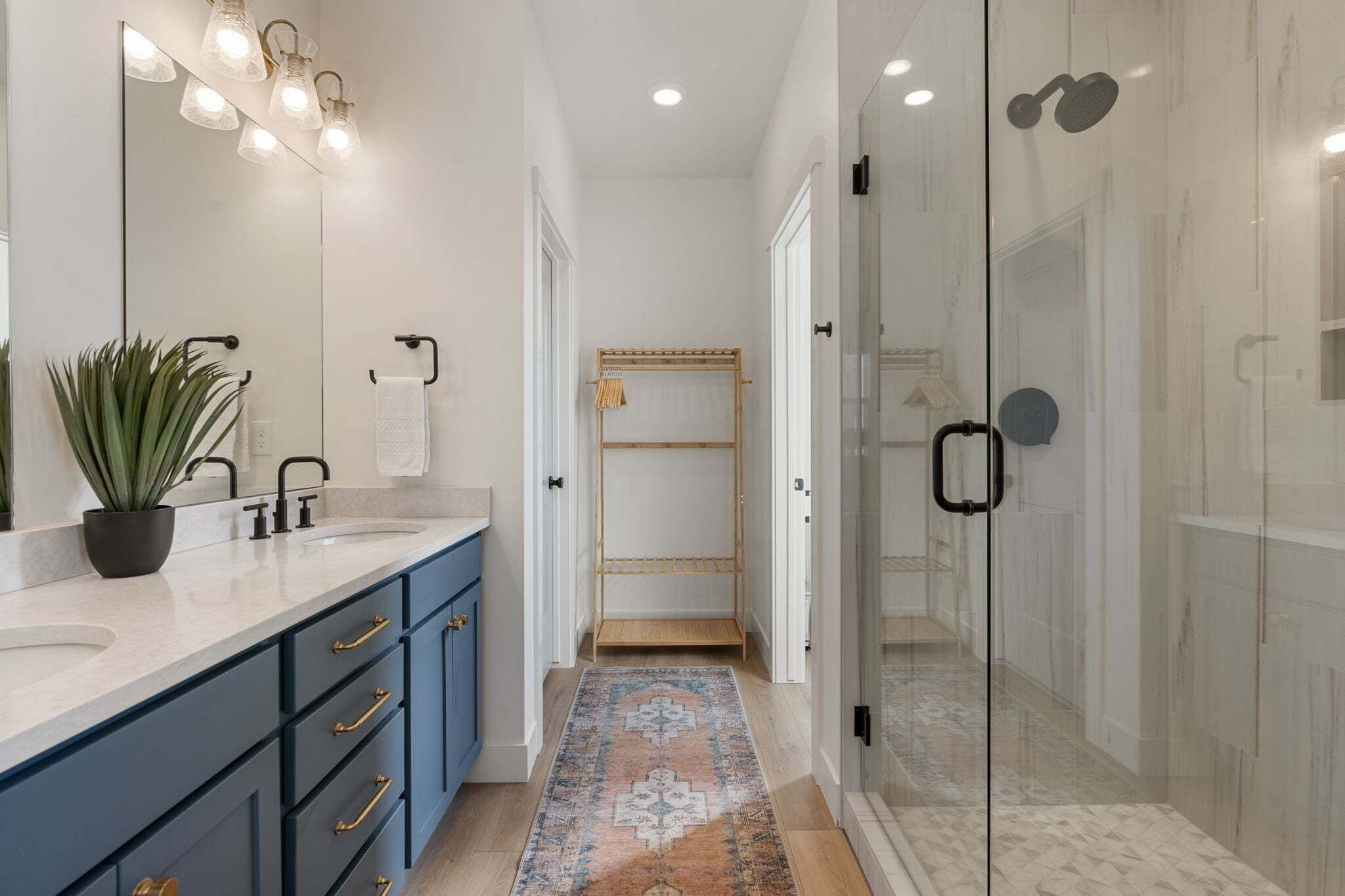 A modern bathroom with a large mirror, dual sinks, and a walk-in shower.