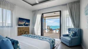 A bedroom with a bed, a blue armchair, a painting, and a view of the ocean. - Sunset & Seaview Poseidon’s Penthouse (Chang Wat Surat Thani)