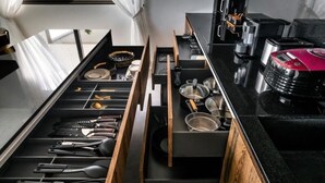 A kitchen with a black countertop, wooden drawer, and various utensils. - Sunset & Seaview Poseidon’s Penthouse (Chang Wat Surat Thani)