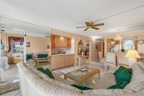 A spacious living area with a sofa, coffee table, and a dining area with chairs and a table. - Menehune Shores, #301 2 Bedroom Condo (Kihei)